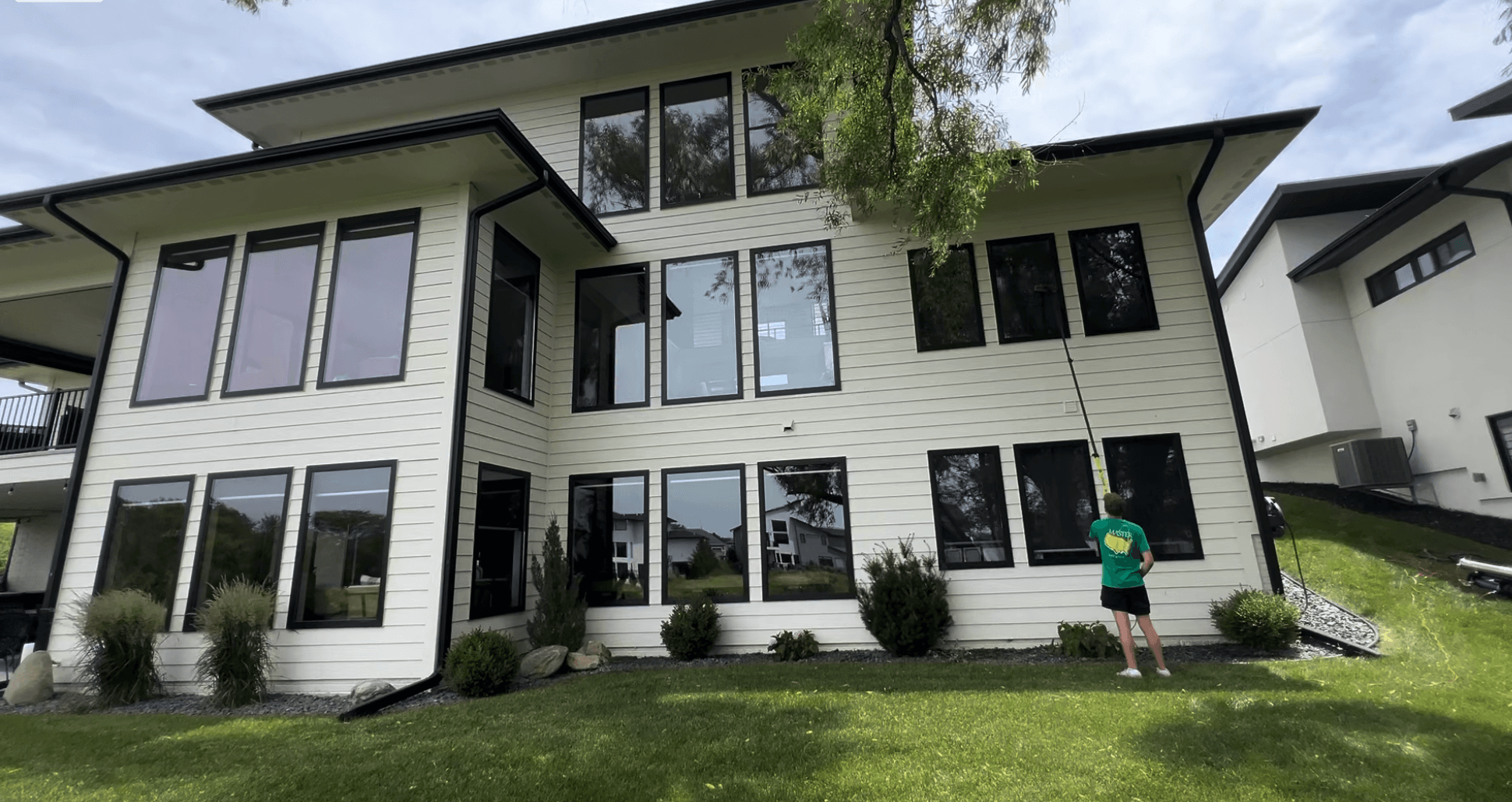 Window Boss technician using a water-fed pole on a modern two-story home