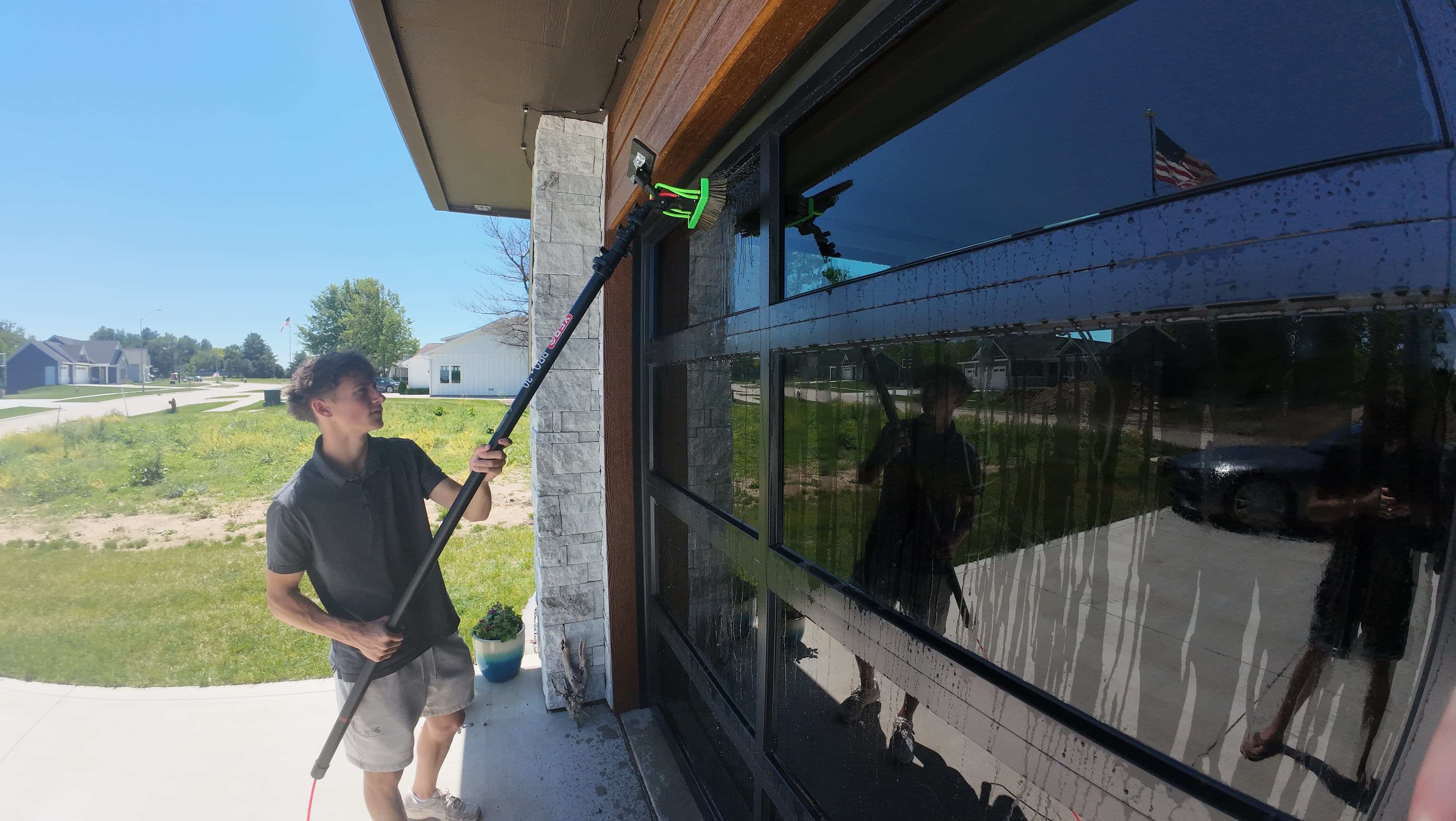 Window Boss technician cleaning floor-to-ceiling garage windows